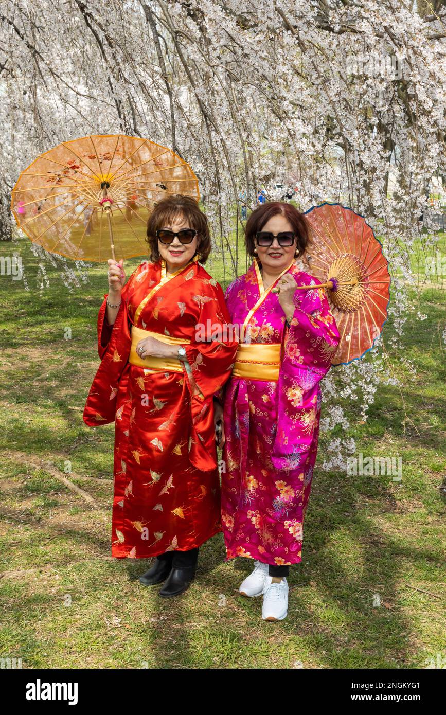 2 donne in kimono rosso con ombrelloni sotto i fiori di ciliegio al bacino del Tidal di Washington, DC Foto Stock