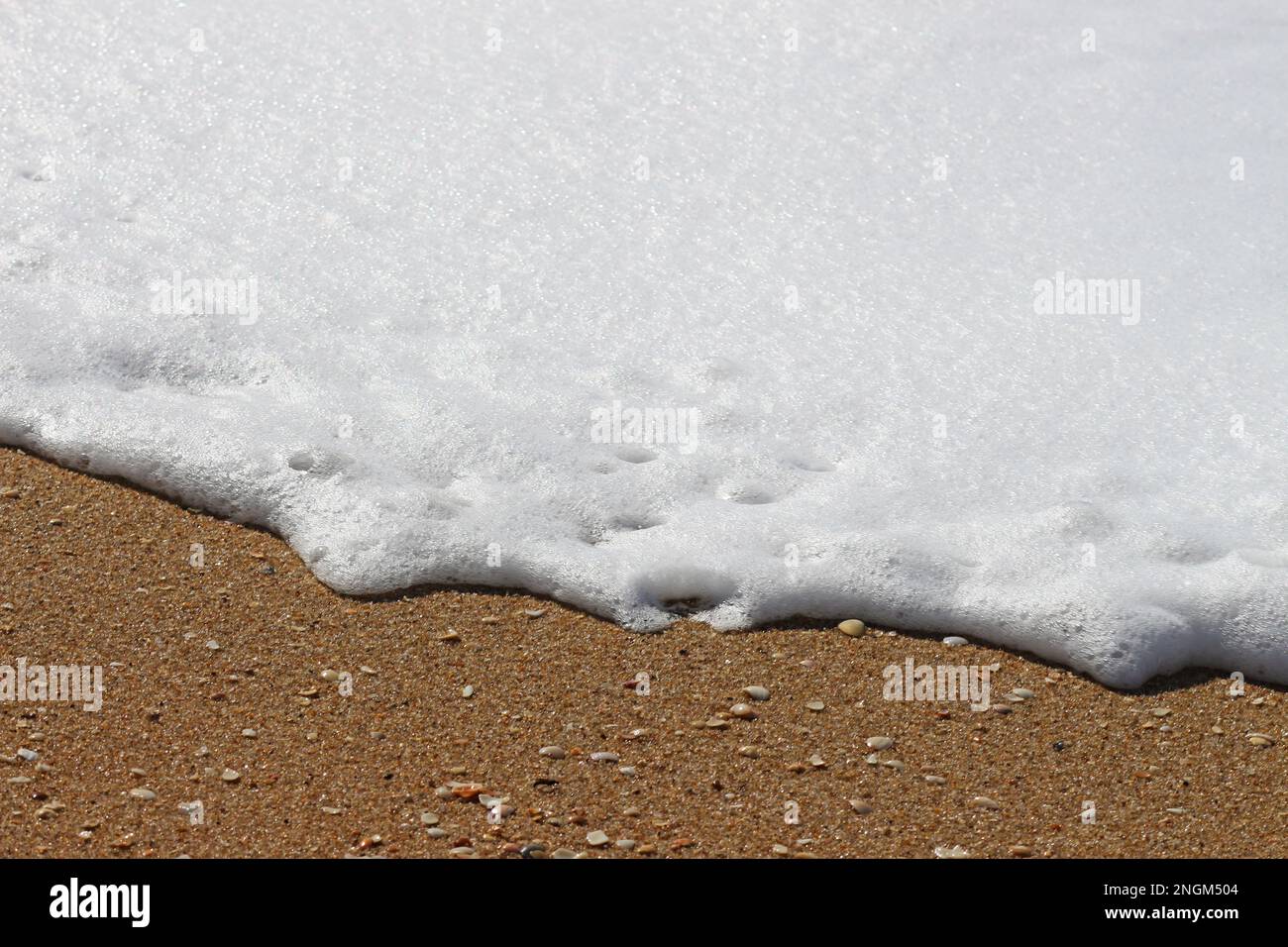 Le onde quando colpiscono la sabbia sulla spiaggia. La schiuma che dipinge immagini astratte e belle. È la natura in tutte le sue forme. Foto Stock