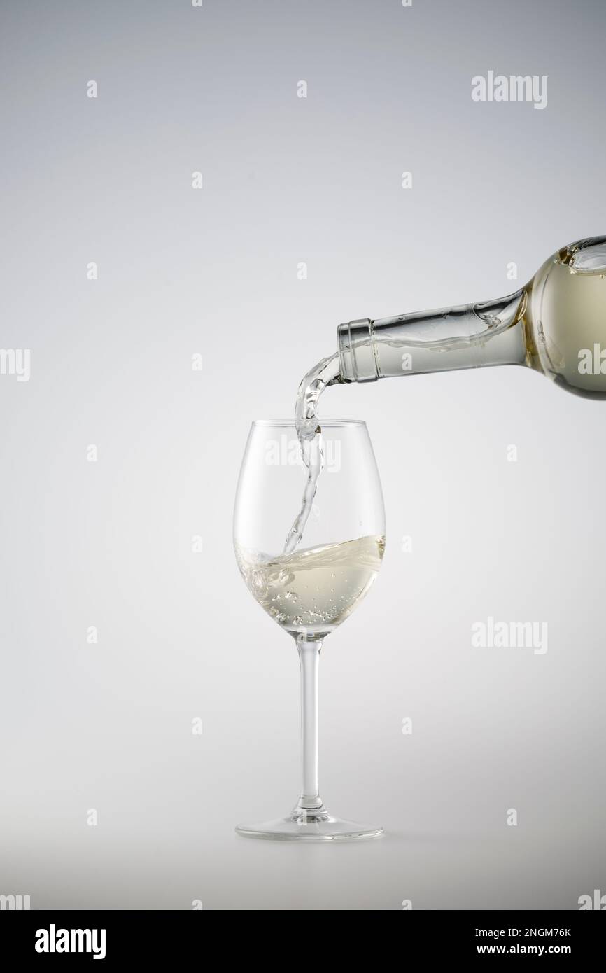 Il vino bianco che viene versato in un bicchiere da vino Foto Stock
