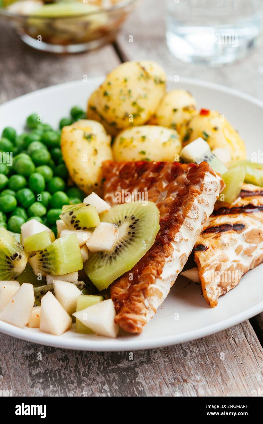 Kiwi e salsa di pere, serviti con tempeh, piselli e patate Foto Stock