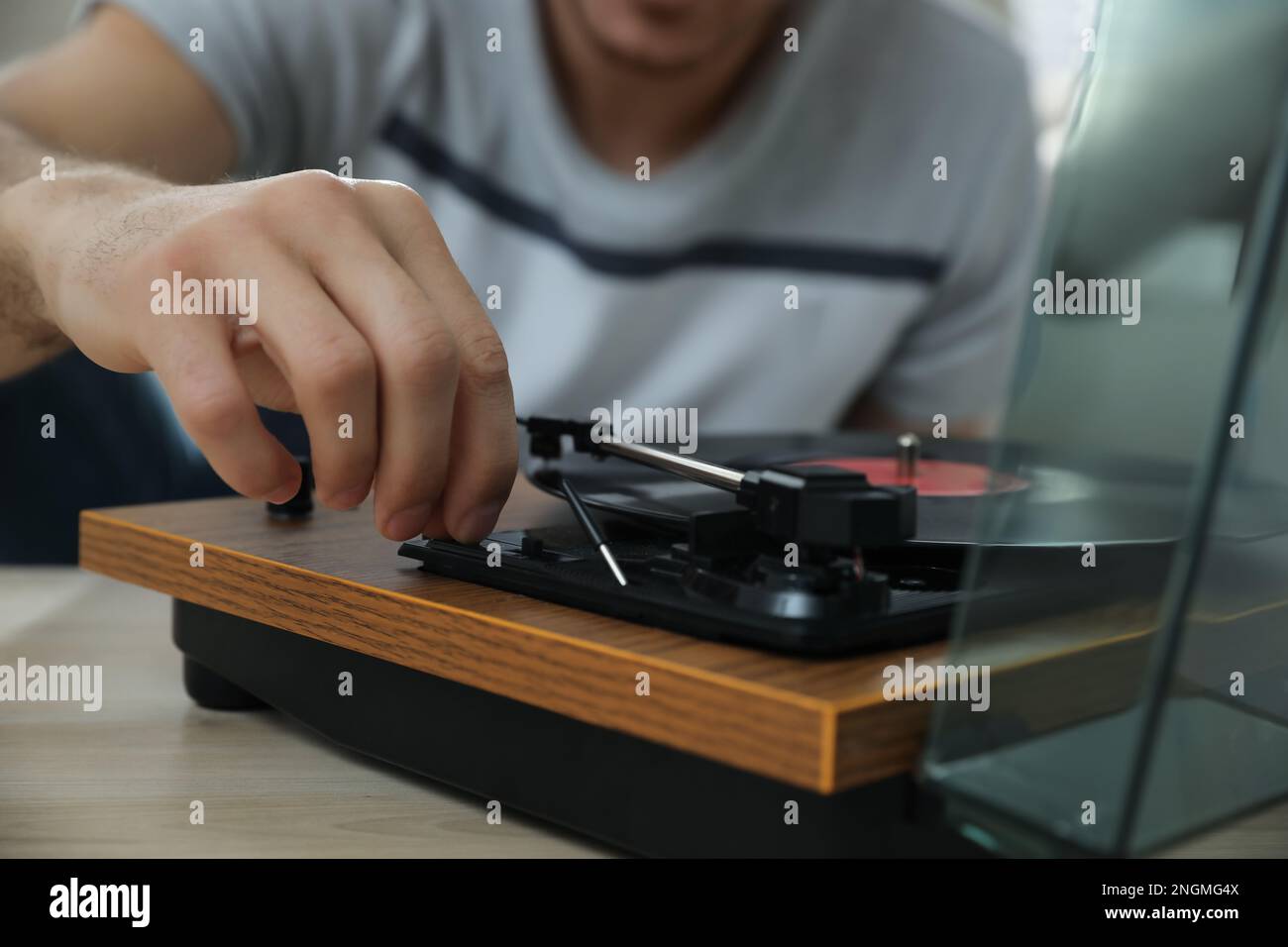 Uomo che usa giradischi al tavolo di legno all'interno, closeup Foto Stock