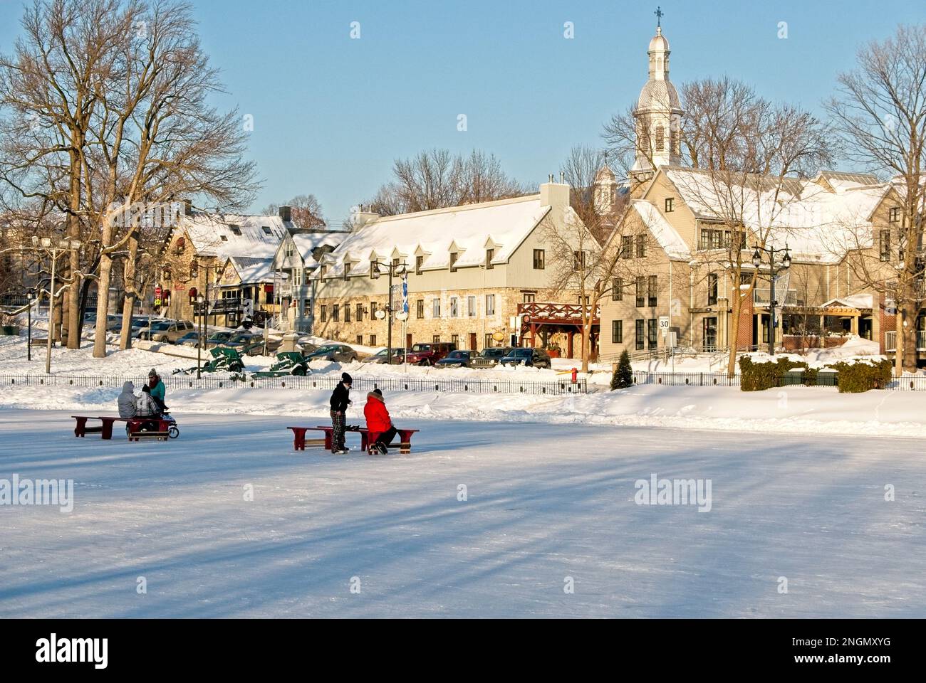 Jeunes qui patinent sur l'étang des Moulins gelé journée ensoleillée hiver. I bambini pattinano sul laghetto ghiacciato a Terrebonne in una giornata di sole. Foto Stock