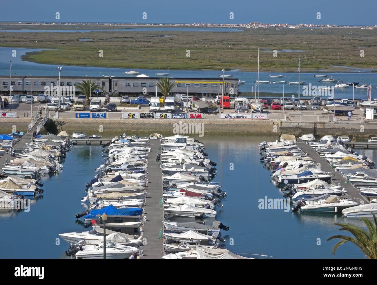 Vista sul porticciolo e sulla palude con il treno che passa da Faro, Algarve, Portogallo Aprile Foto Stock