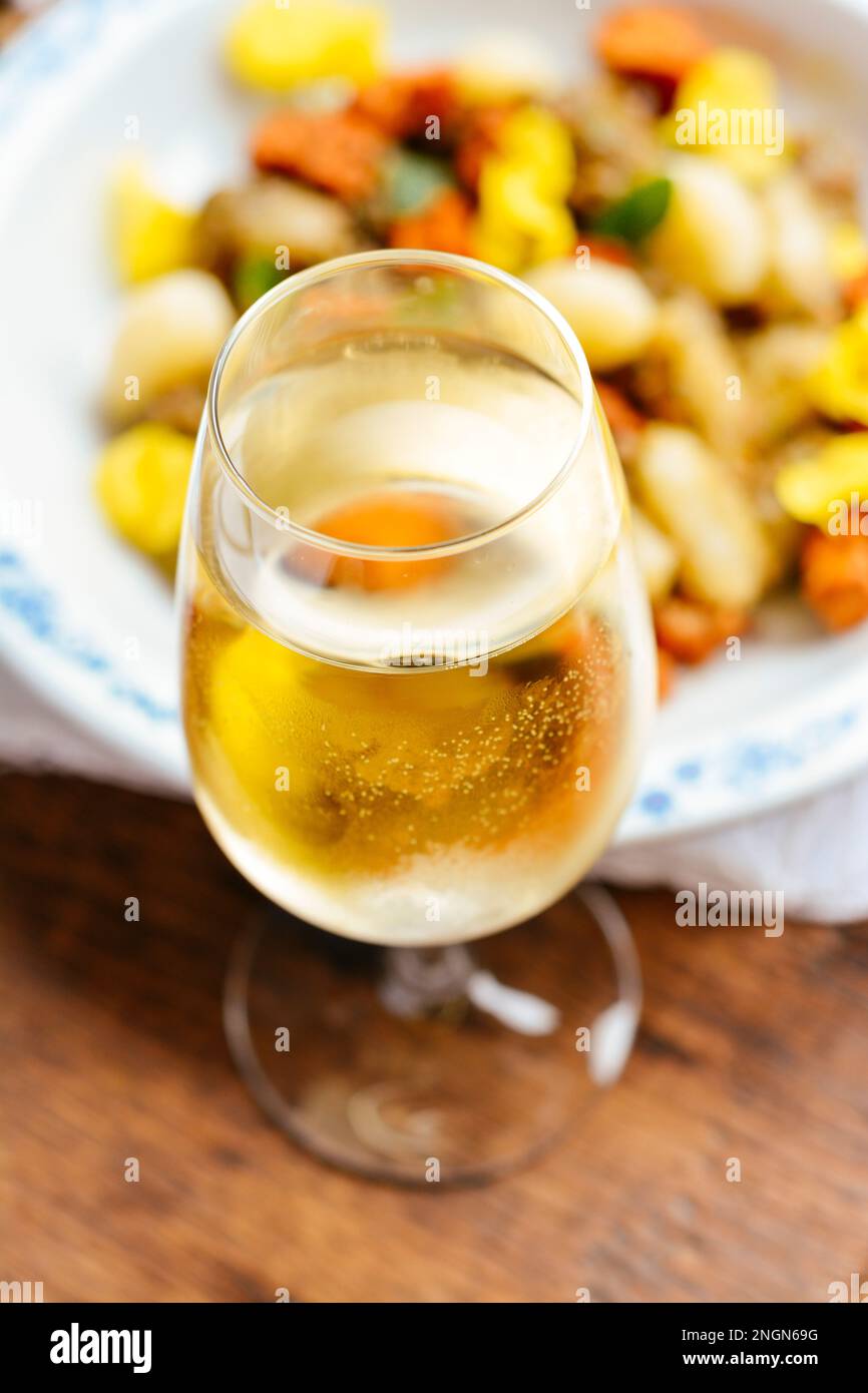 Bicchiere di vino bianco nella parte anteriore del piatto con gnocchi. Foto Stock