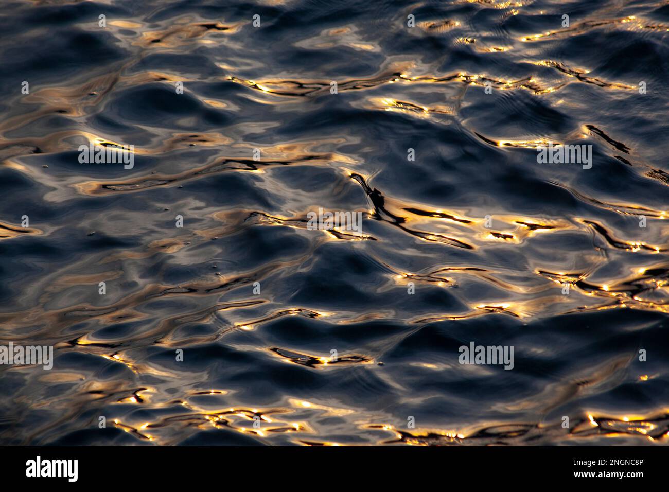 Increspature astratte dell'oceano, riflessi al tramonto, motivi naturali Foto Stock