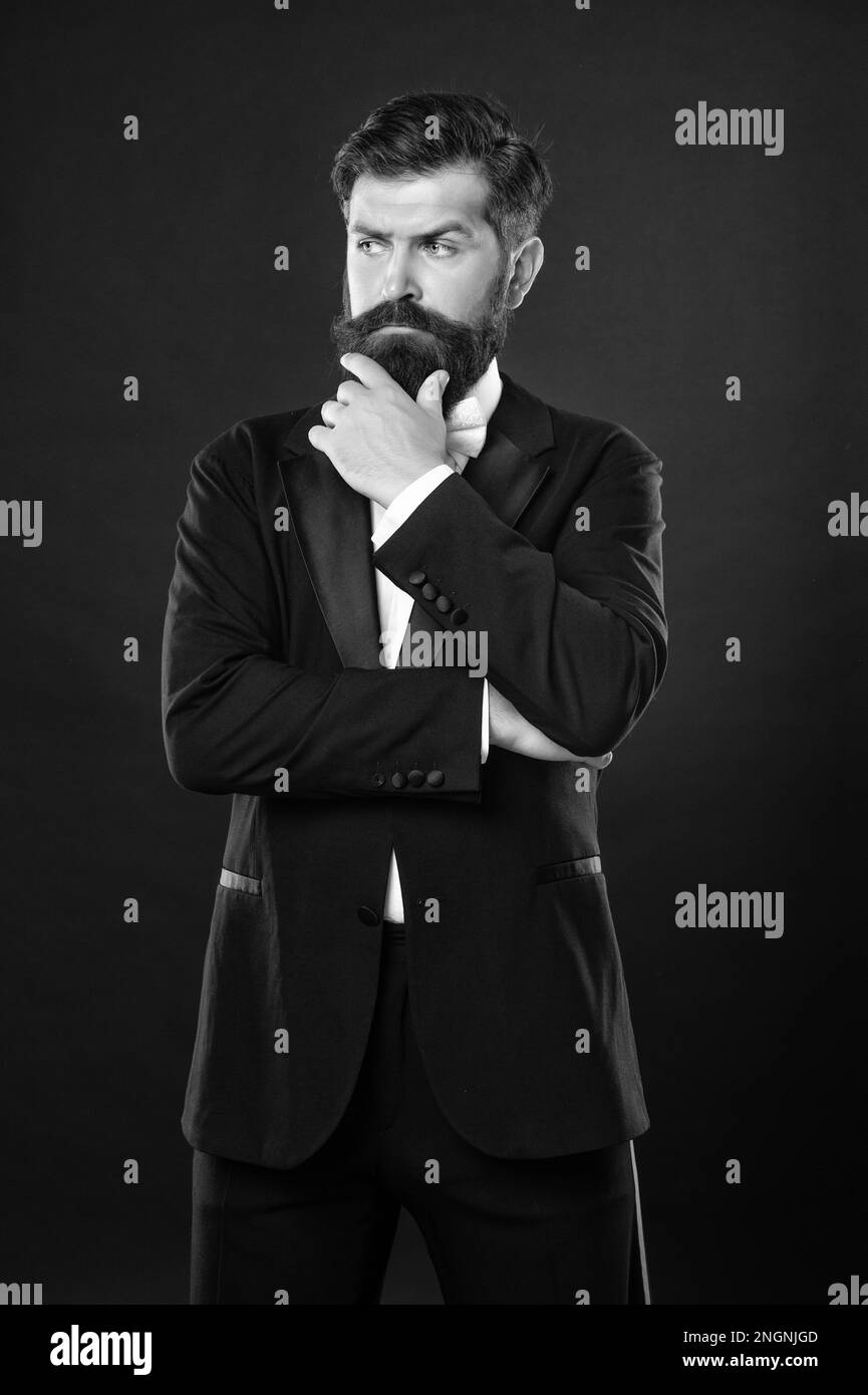 uomo barbuto in smoking su sfondo nero, abbigliamento maschile. Foto Stock