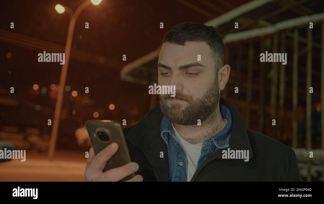 Messaggio al barbuto di Tall Young Man al telefono nello scenario innevato Foto Stock