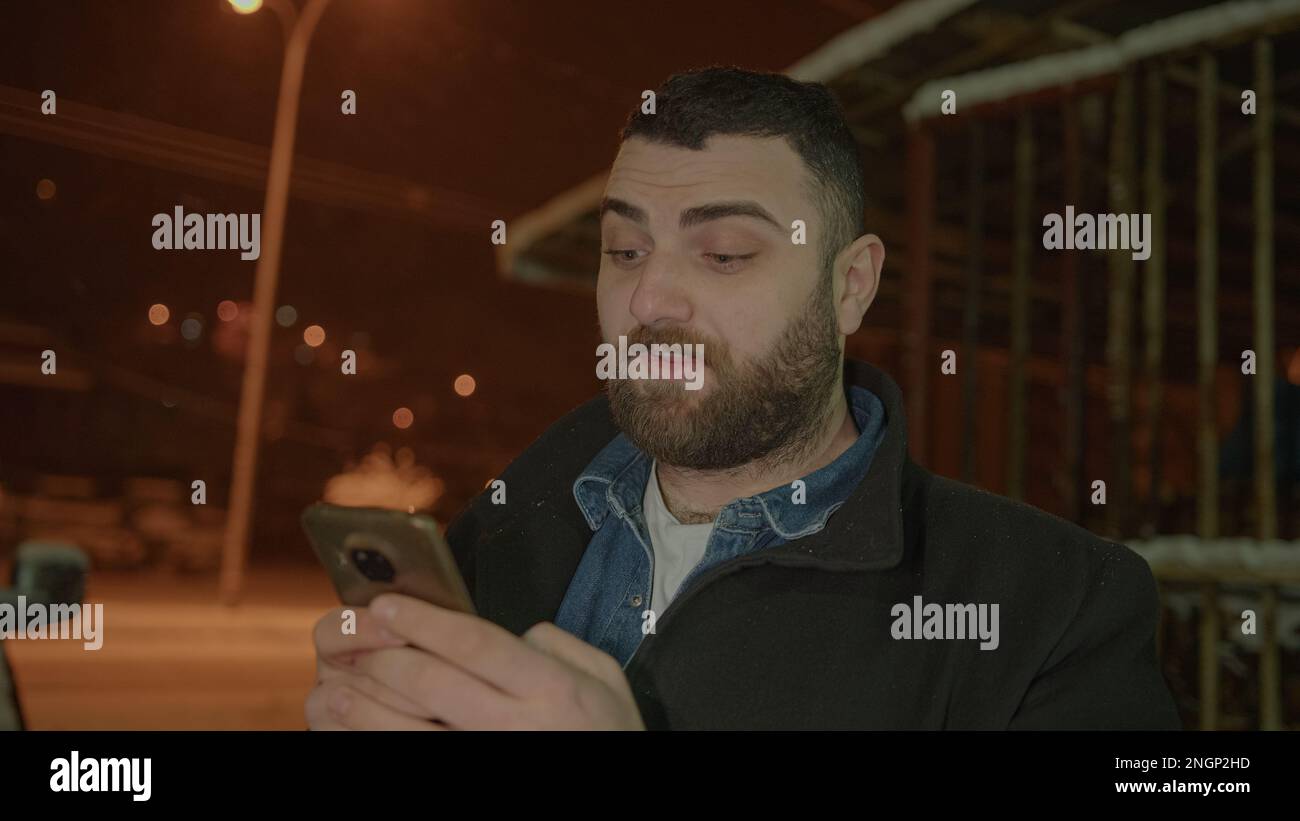 Shocked faccia Bearded Tall Young Man messaggi al telefono nel paesaggio innevato Foto Stock