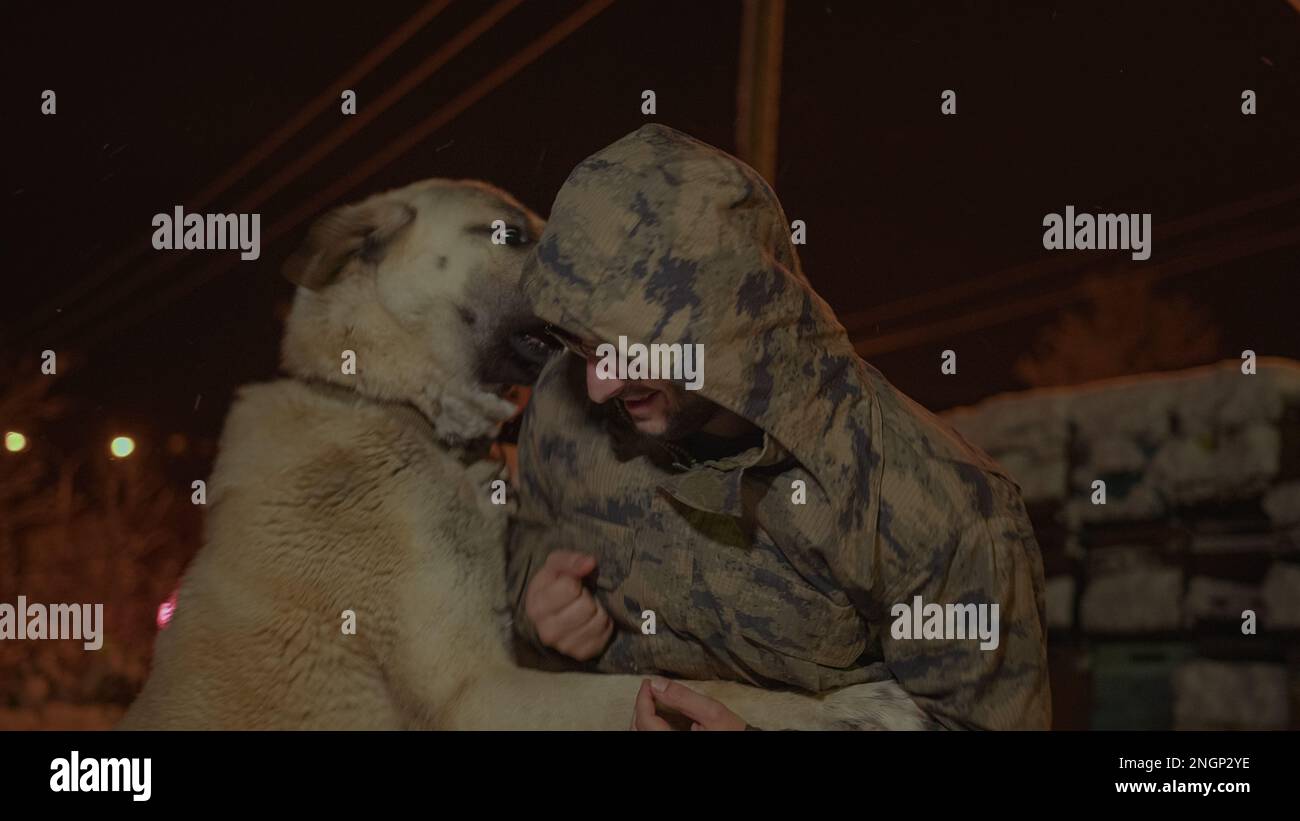 Giovane uomo rivestito da militari che gioca con un cane di Sivas Kangal nel tempo innevato Foto Stock