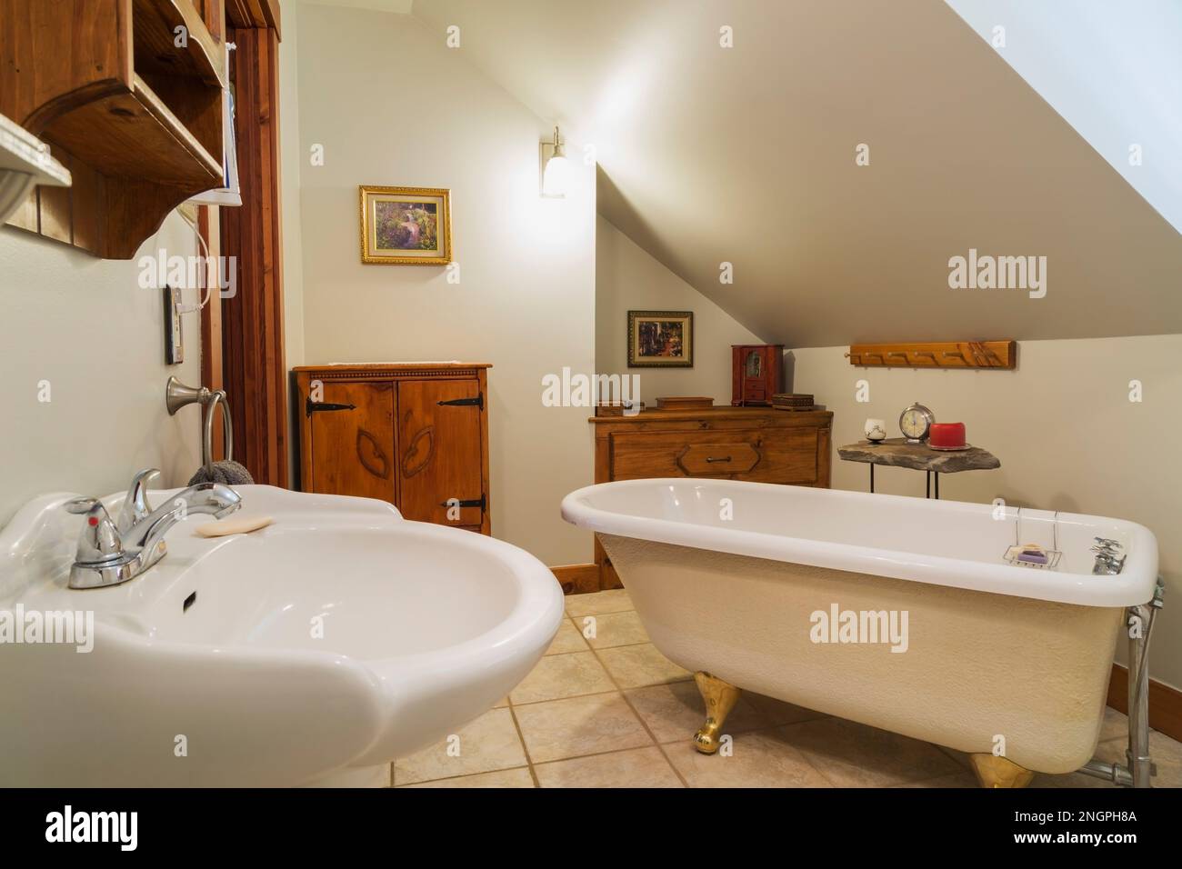 Lavabo a piedistallo bianco, vasca da bagno a zampa di artiglio e antichi armadi in legno di pino nel bagno privato con piastrelle in ceramica all'interno di una casa vittoriana contemporanea degli anni '1990. Foto Stock