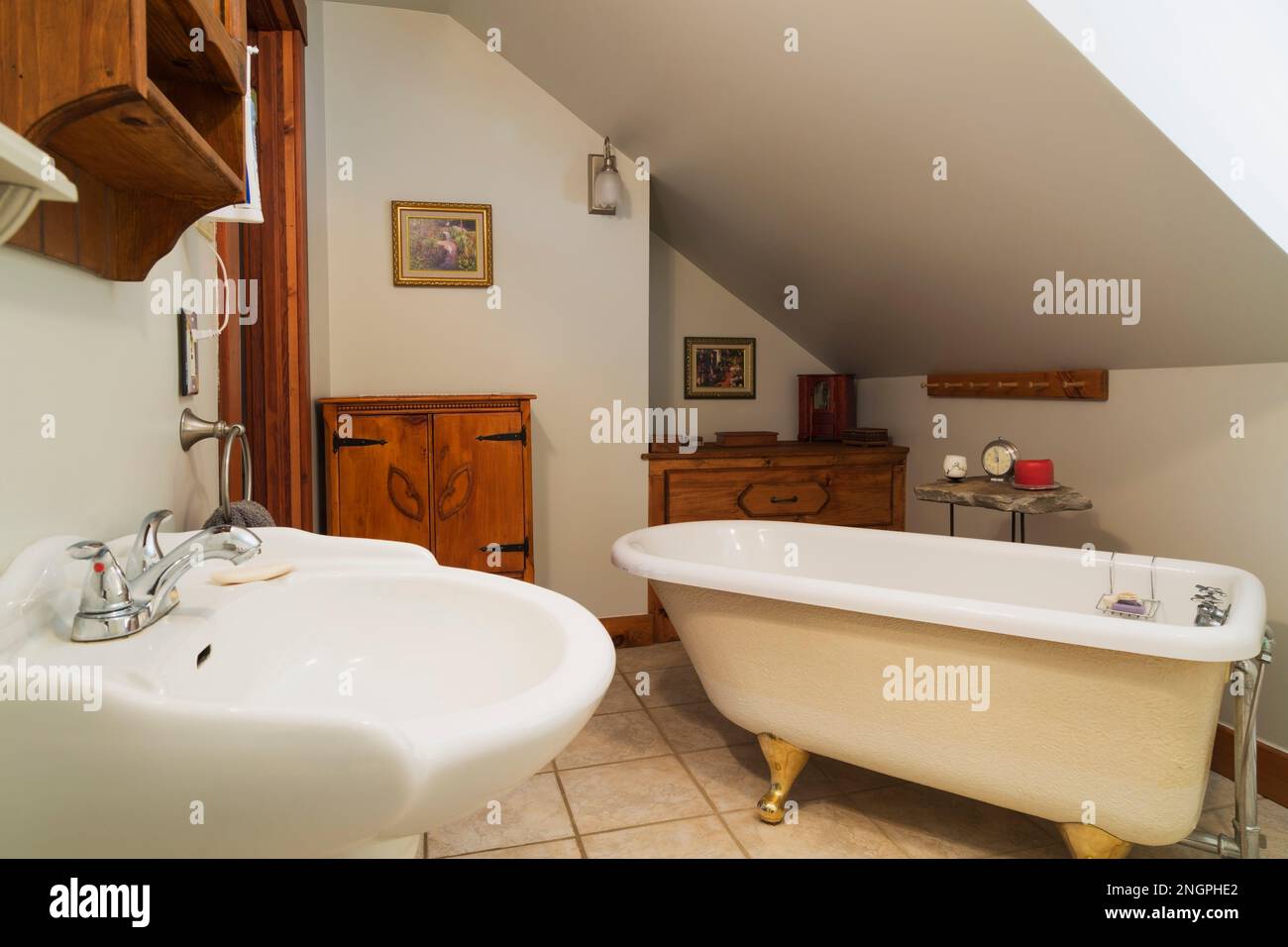 Lavabo con piedistallo bianco, vasca da bagno con base a zampa di leone e antichi armadietti in legno di pino in bagno con piastrelle in ceramica al piano superiore all'interno di 1990s V contemporanei Foto Stock