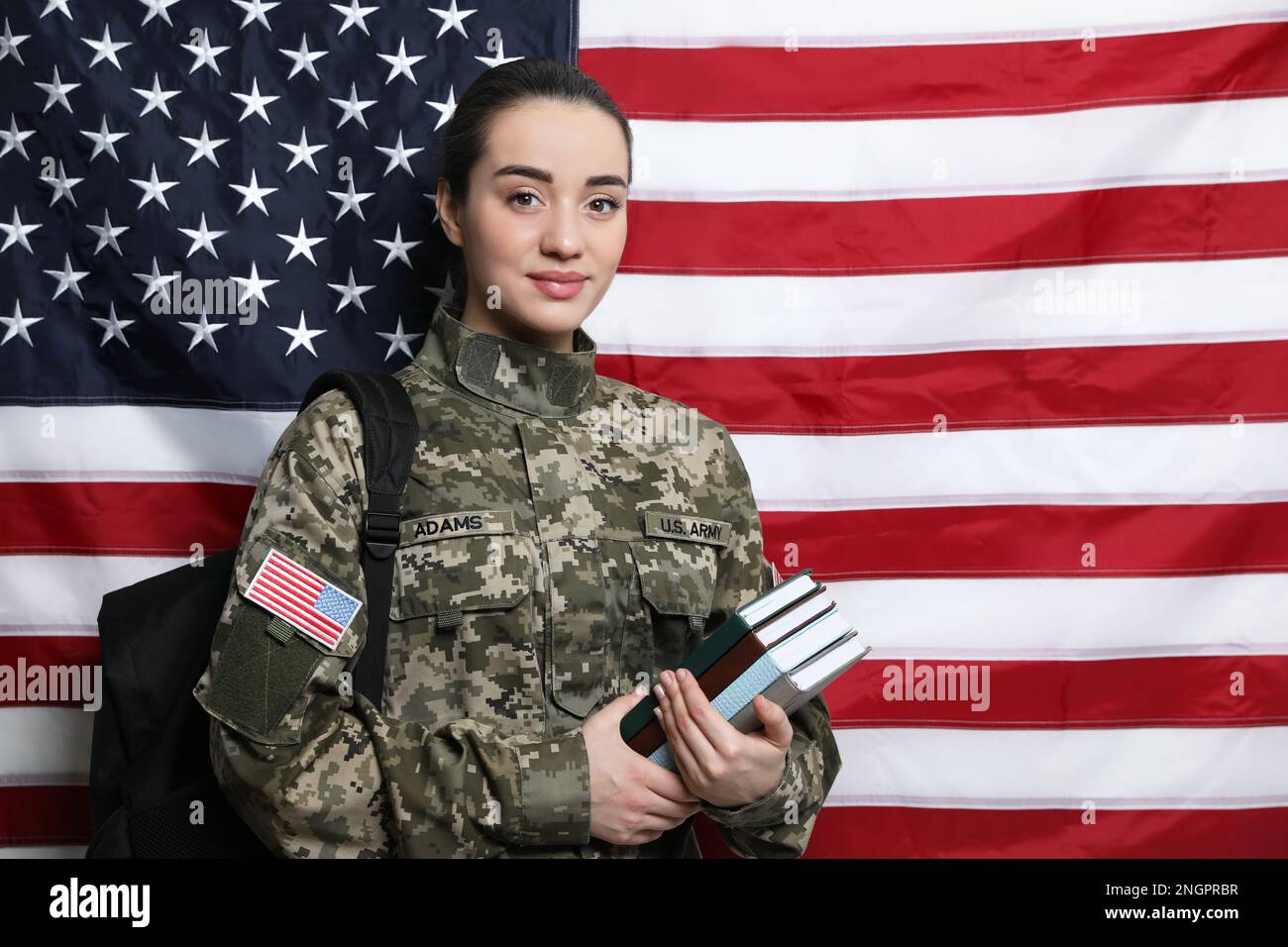 Soldato femminile con zaino e libri vicino alla bandiera degli Stati Uniti, spazio per il testo. Educazione militare Foto Stock