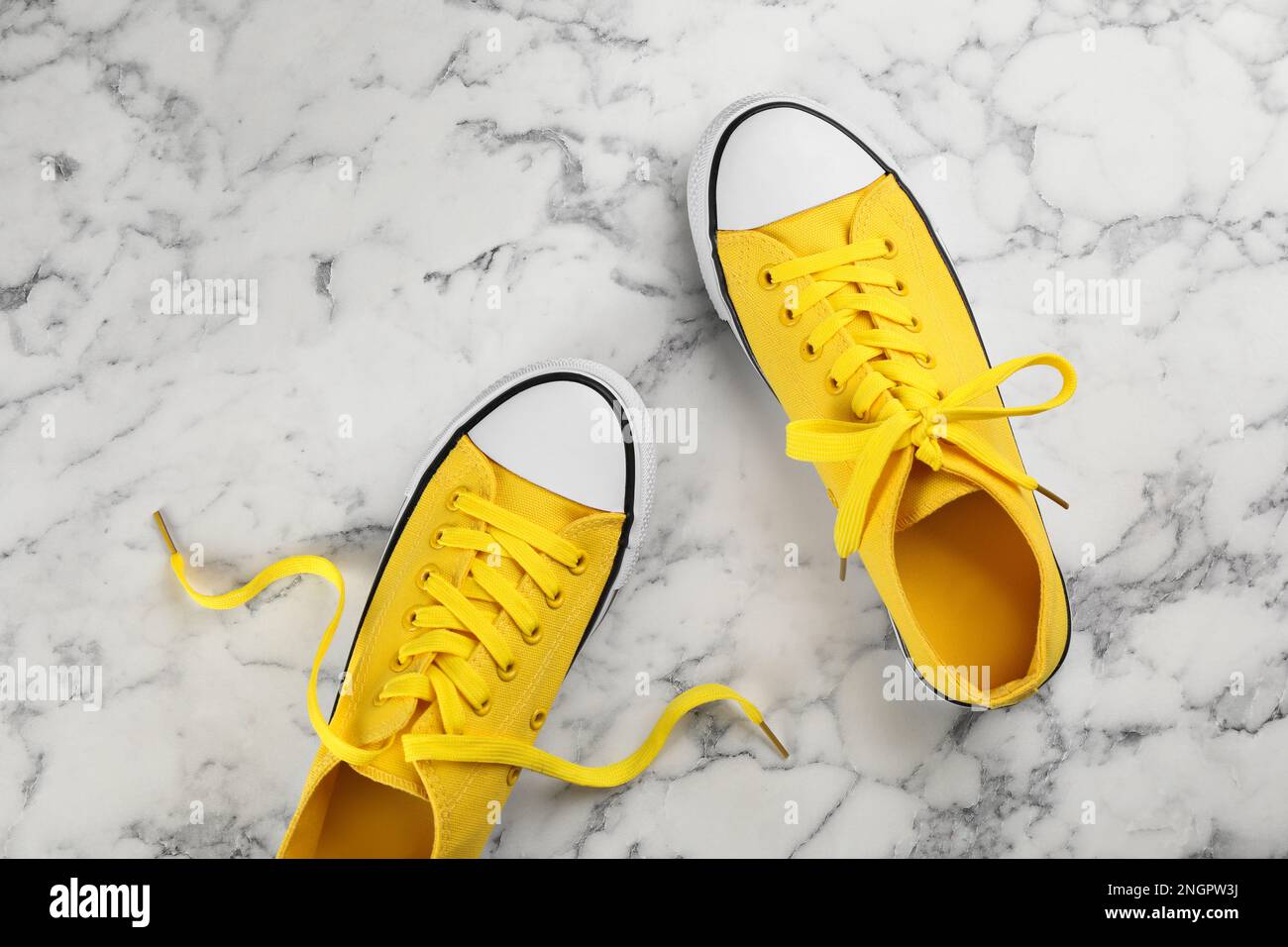 Paio di sneaker gialle su tavolo in marmo bianco, a posa piatta Foto Stock