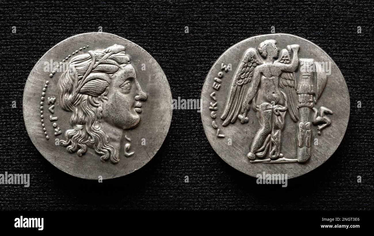 Antica moneta greca, macro vista del denaro con ritratto umano e dio alato. Vecchia moneta rara isolata su sfondo scuro. Tema della Grecia, ellenistico, un Foto Stock