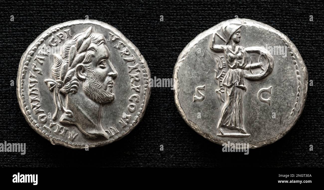 Antica moneta romana, denaro dell'imperatore Antonino Pio, dea Minerva sul retro. Macro vista del denario, vecchia moneta rara isolata su sfondo scuro Foto Stock