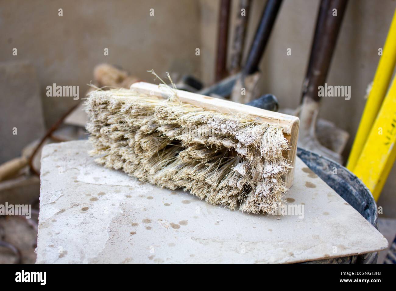 Primo piano, messa a fuoco selettiva su un pennello sintetico bianco usato. Questa spazzola viene utilizzata nell'industria edile durante l'intonacatura. Foto Stock