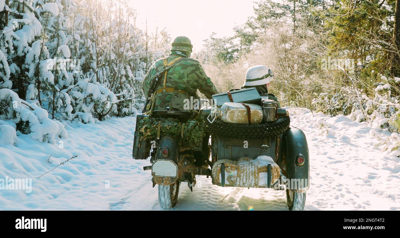 Re-enactors vestito come soldati tedeschi Wehrmacht fanteria della seconda guerra mondiale alla guida di Old Tricar, motocicletta a tre ruote nella foresta innevata d'inverno Foto Stock