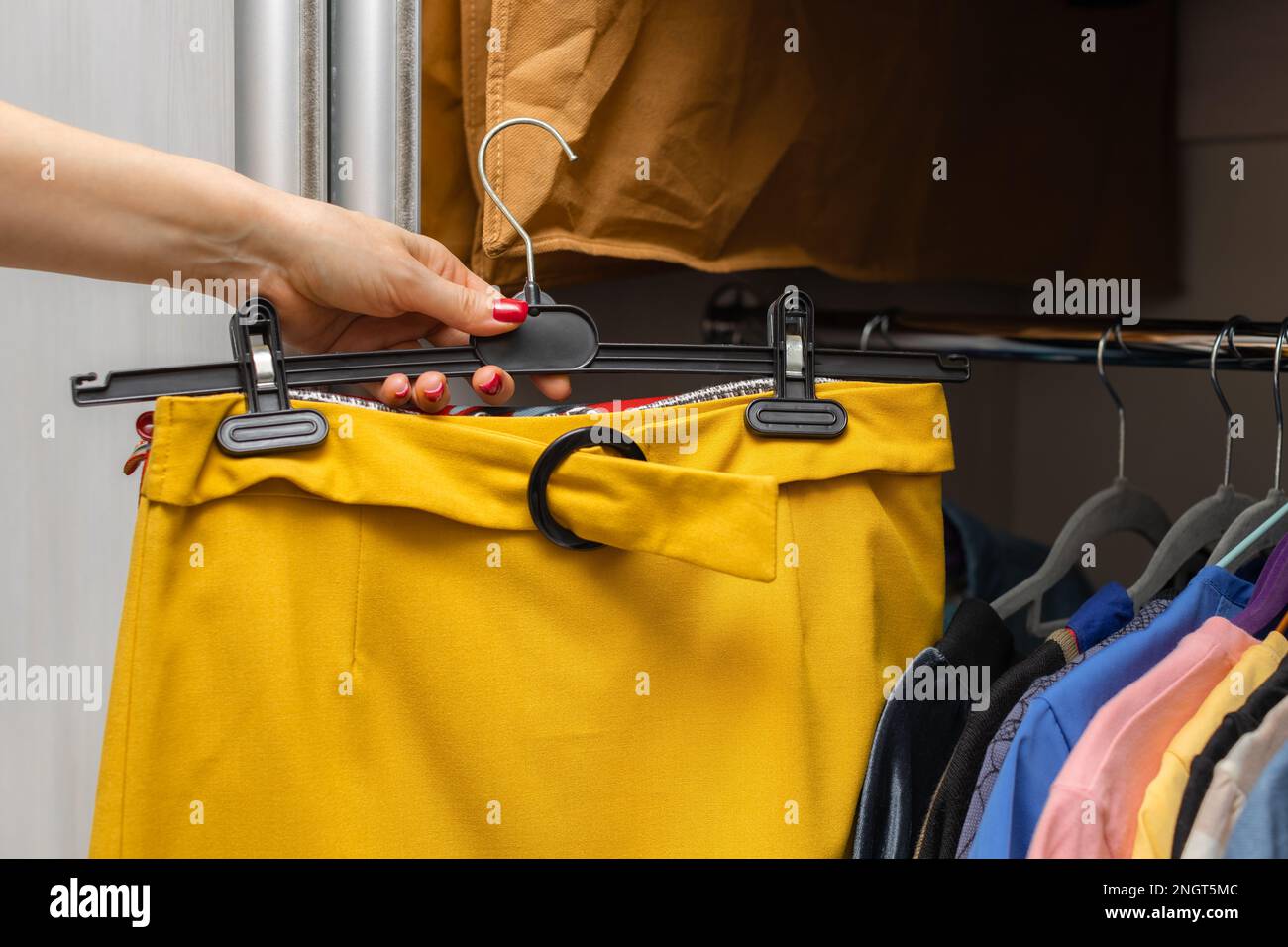 una donna prende una gonna luminosa da un guardaroba. donna che prova su gonna gialla. Foto Stock