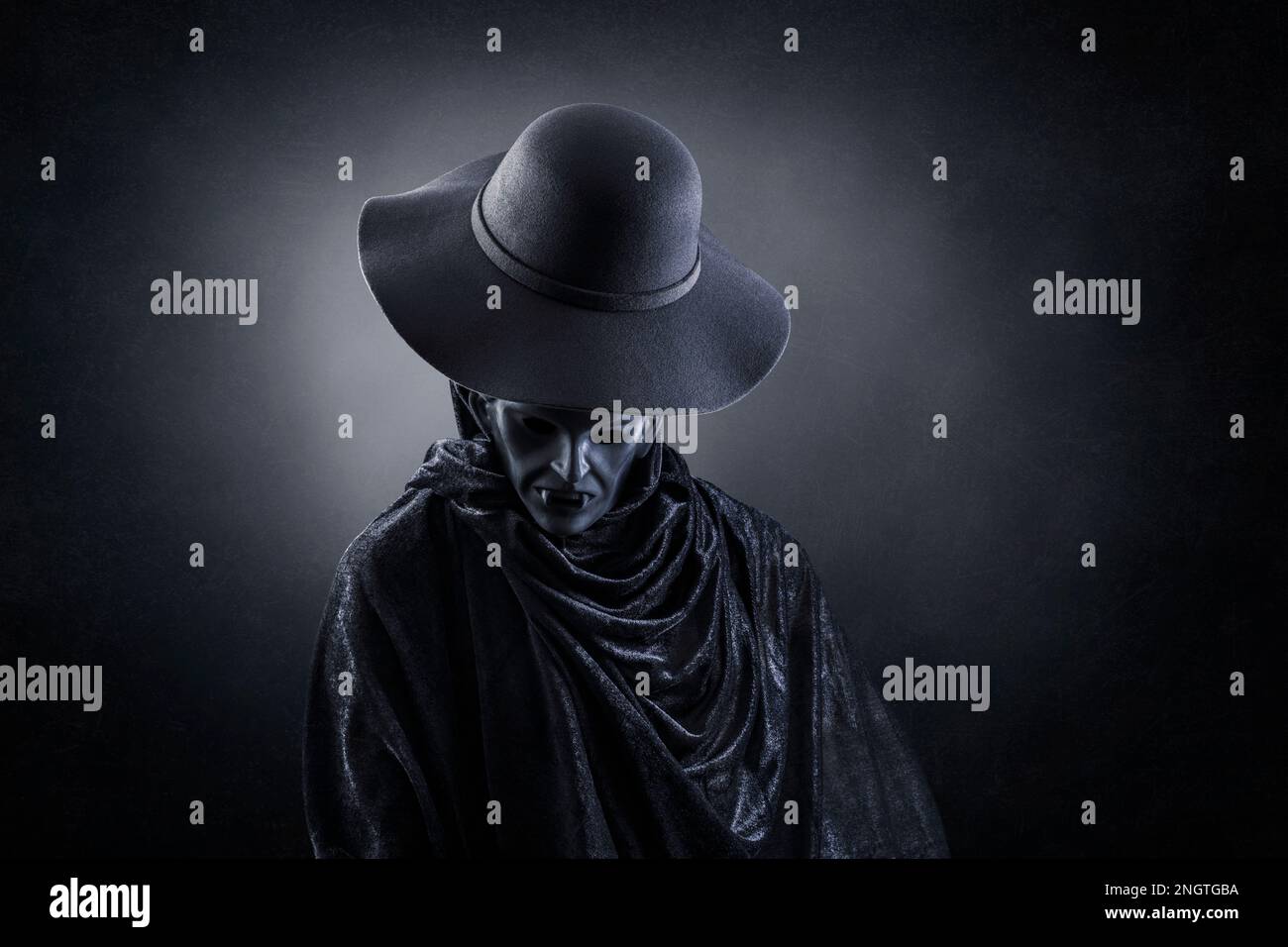 Vampiro con vecchio cappello su sfondo oscuro e misterico Foto Stock