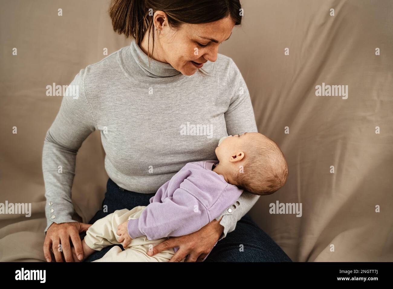 Madre felice che si prende cura del suo bambino piccolo che dorme nelle sue braccia a casa - famiglia di concetto e maternità Foto Stock