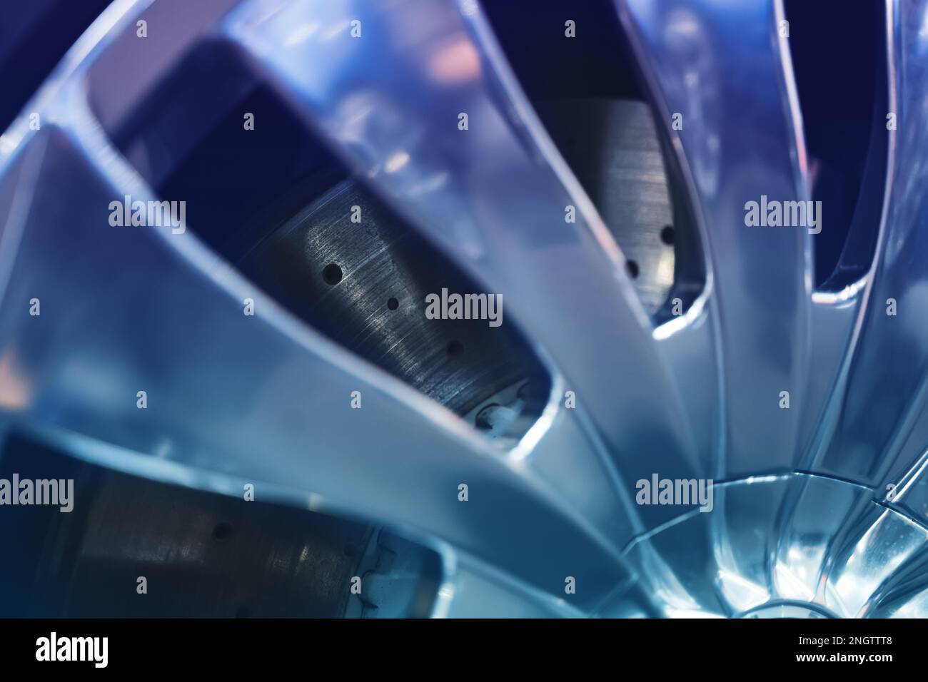 primo piano della rottura del disco fisso aerato lucido con perforazione vista attraverso la ruota del cerchio cromata argento Foto Stock