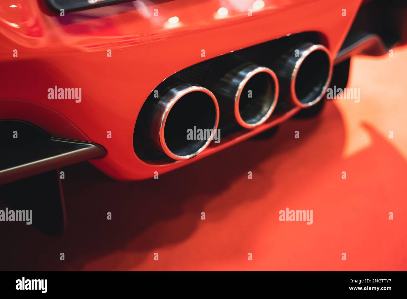 dettaglio vista posteriore dei tripli tubi di scarico delle auto sportive rosse Foto Stock