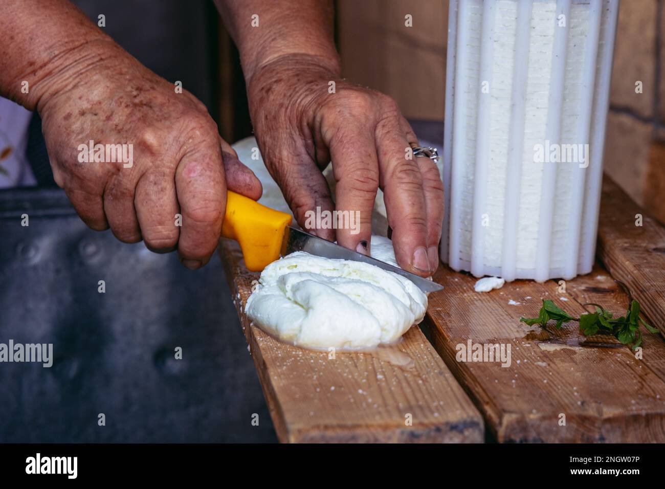 La signora Sofia taglia le chesse di Halloumi a Sofia e la casa tradizionale di Andreas nel villaggio di Letymbou nel distretto di Paphos, paese insulare di Cipro Foto Stock