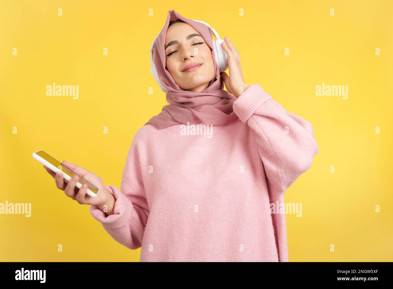 Donna musulmana rilassata che ascolta musica con il cellulare Foto Stock