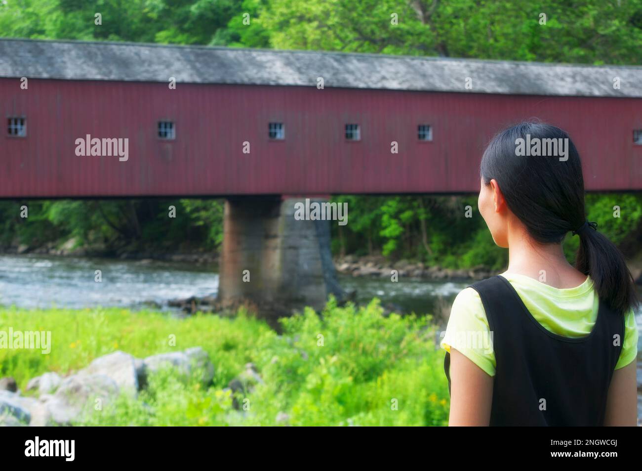 Una donna cinese che guarda il ponte coperto della cornovaglia occidentale sul fiume housatonic sullo sfondo. Foto Stock