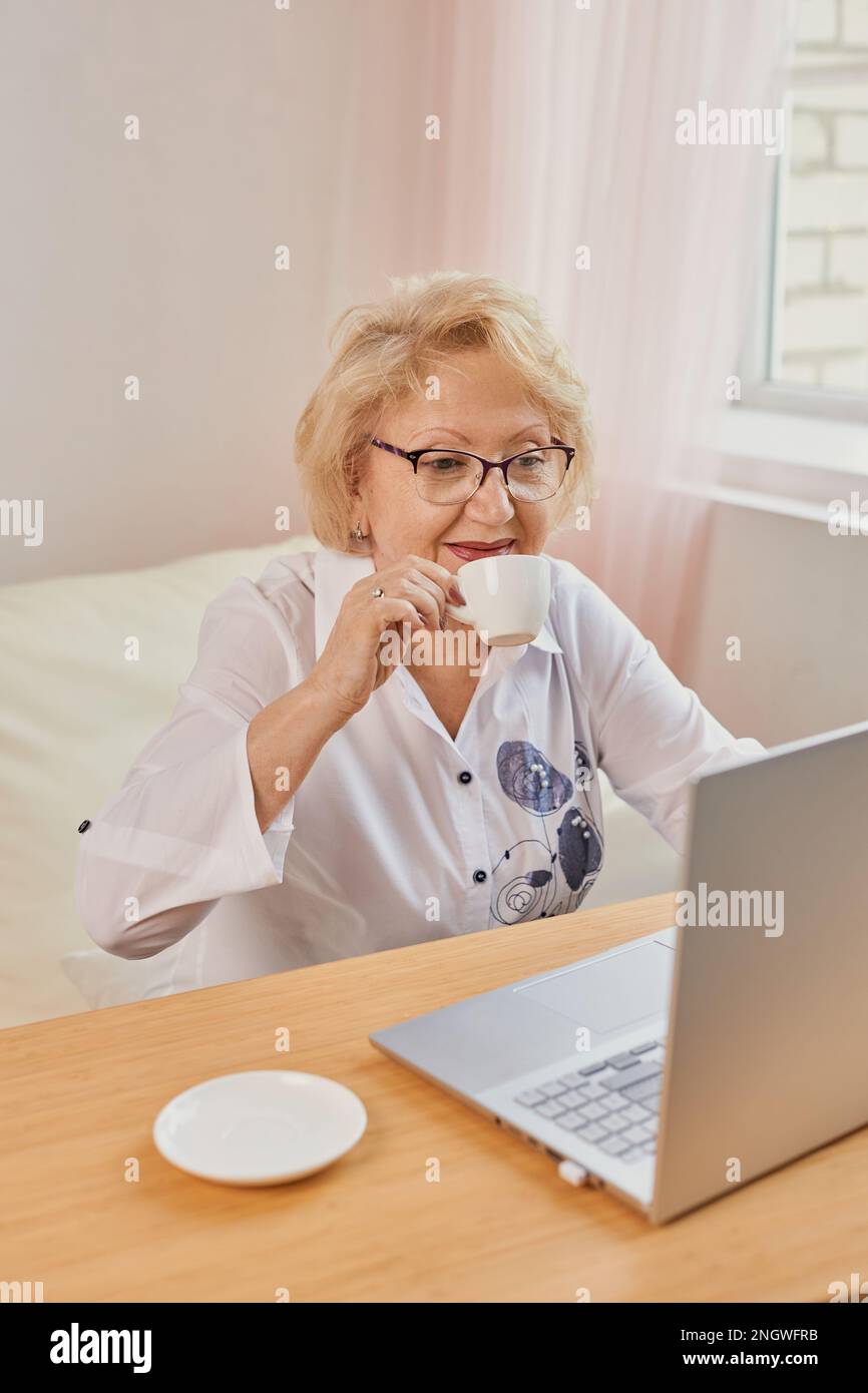 Felice matura anziana di mezza età donna che legge buone notizie guardando il laptop Foto Stock