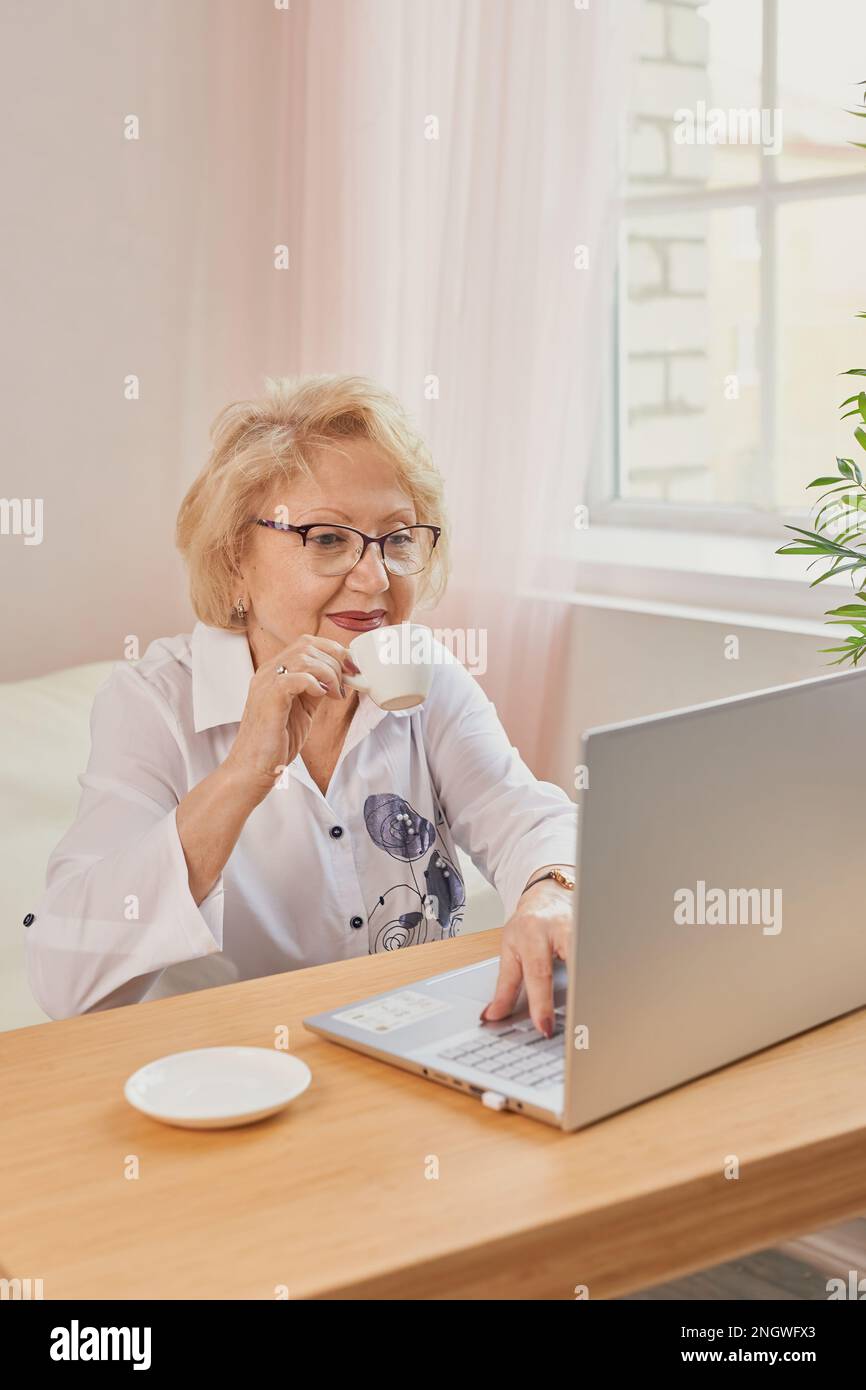 Felice matura anziana di mezza età donna che legge buone notizie guardando il laptop Foto Stock