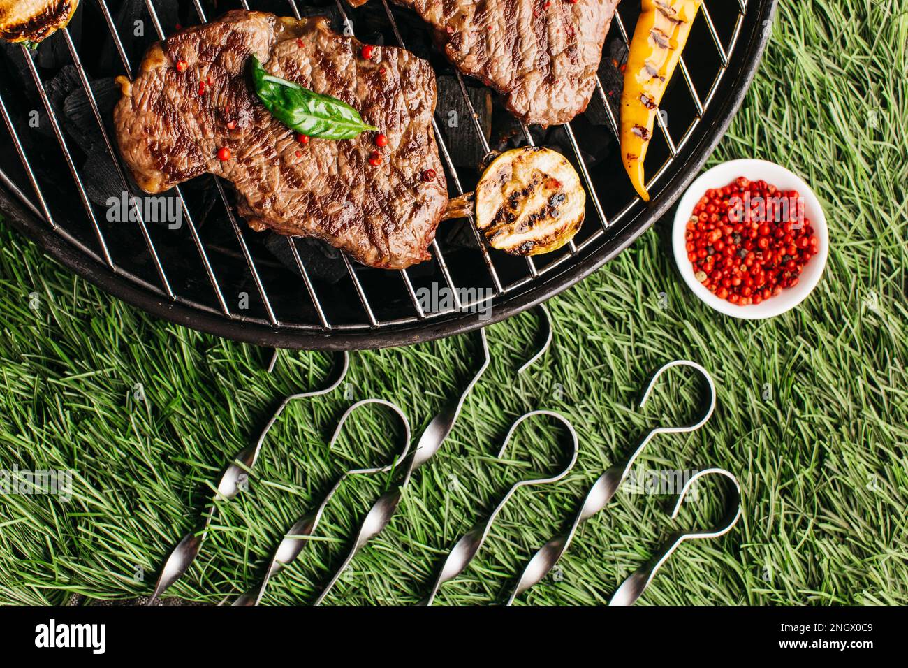 bistecca di verdure alla griglia con spiedino metallico barbecue griglia verde erba sfondo Foto Stock