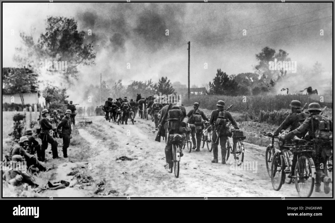WW2 OPERAZIONE BARBAROSSA Una colonna di soldati tedeschi nazisti con biciclette entra in un villaggio sovietico sul fronte orientale che è già stato torcito dall'avanzare delle forze naziste. Data giugno 1941 Foto Stock