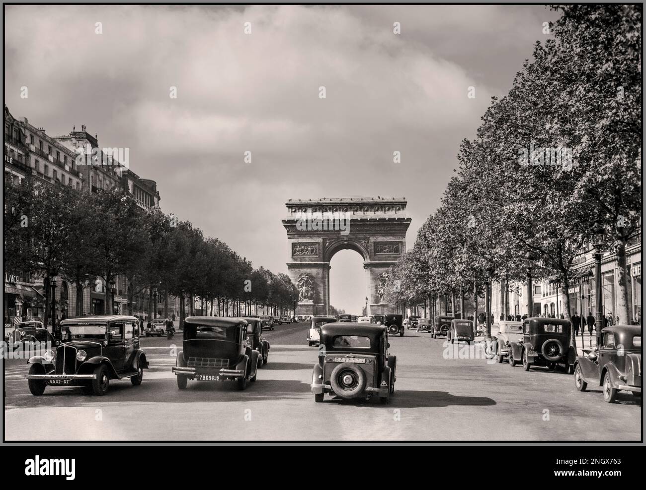 PARIGI vintage anni '30 retrò Parigi 1936 Arc de Triomphe e il traffico sugli Champs-Elysees tra cui Parigi Renault Taxi e persone che indossano gli stili e la moda del giorno. Pre WW2 Street scene archivio francese B&W fotografo Willem van de poll Foto Stock
