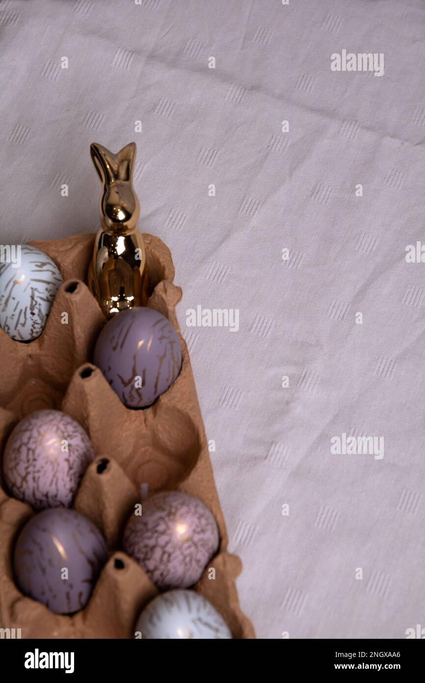 Foto di uova di pollo colorate giacenti in un vassoio di uova e un coniglietto di Pasqua su un tavolo Foto Stock
