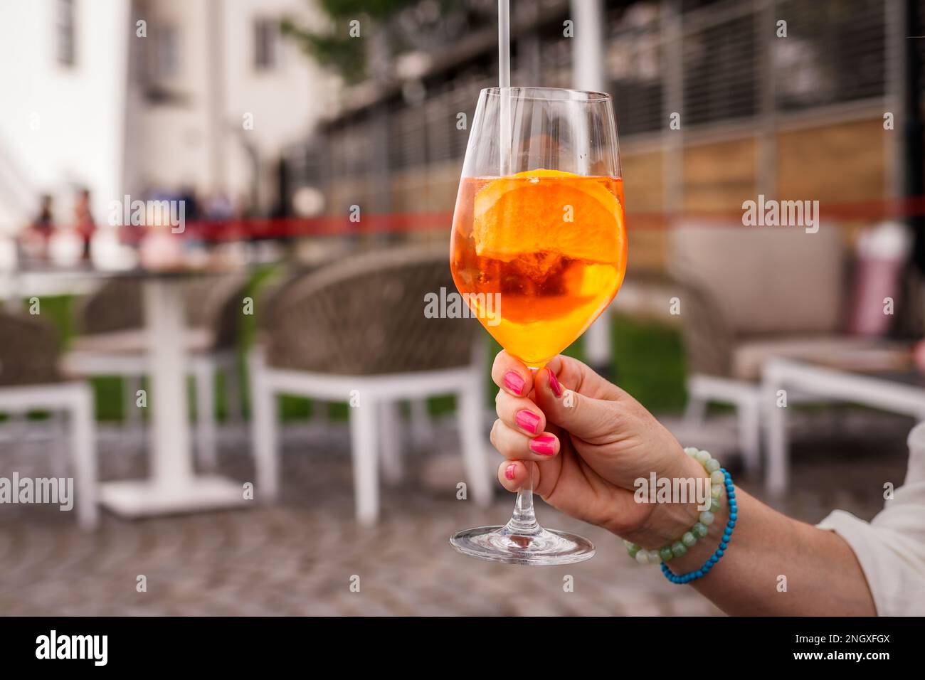 Donna che tiene un cocktail Spritz Veneziano nel ristorante all'aperto di Vienna Foto Stock