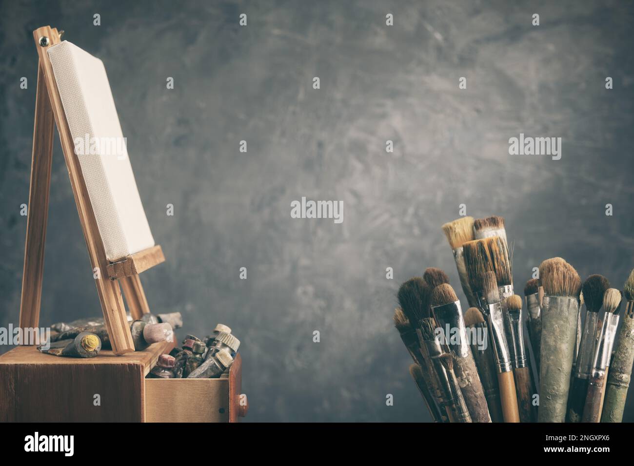 Attrezzatura artistica in studio: Tela d'artista su cavalletto in legno, tubi e pennelli - pennelli artistici usati per dipingere con Foto Stock