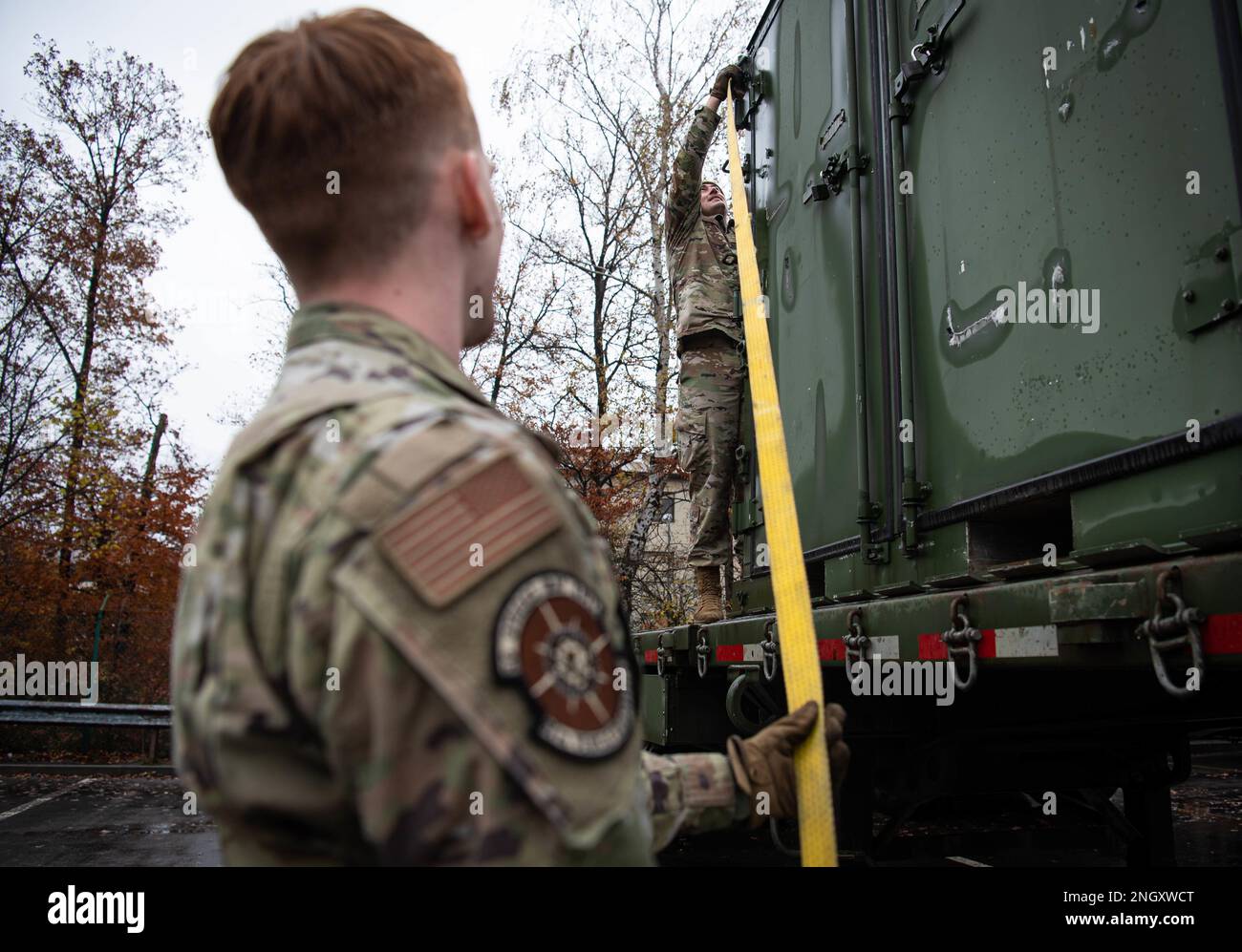 STATI UNITI Air Force Airman 1st Class Tyler Benner, destra, 86th Vehicle Readiness Squadron Vehicle Operator e Airman 1st Class Jeremy Evans, sinistra, 86th VRS Ground Transport Operator, fissare un contenitore di spedizione presso la base aerea di Ramstein, Germania, 30 novembre 2022. Benner ha fatto mettere in pausa la sua vita quando costretto a trascorrere mesi in ospedale a causa di una rara condizione medica che ha causato la crescita di un ascesso sul suo fegato. Aggregatibacter aphrophilus, un comune batterio residente in bocca, ha causato il suo sangue a diventare settico e ha portato alla crescita di un ascesso di baseball-dimensione nel suo fegato. Foto Stock