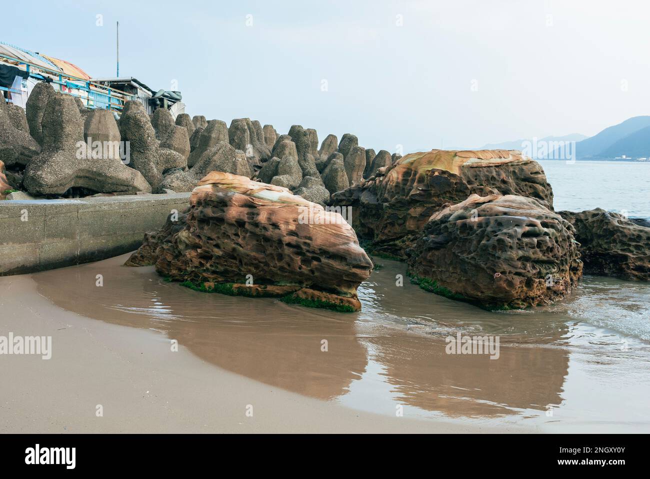 Spiaggia di sabbia su sfondo nuvoloso. Ci sono blocchi di dolos disposti per evitare le onde. Foto Stock