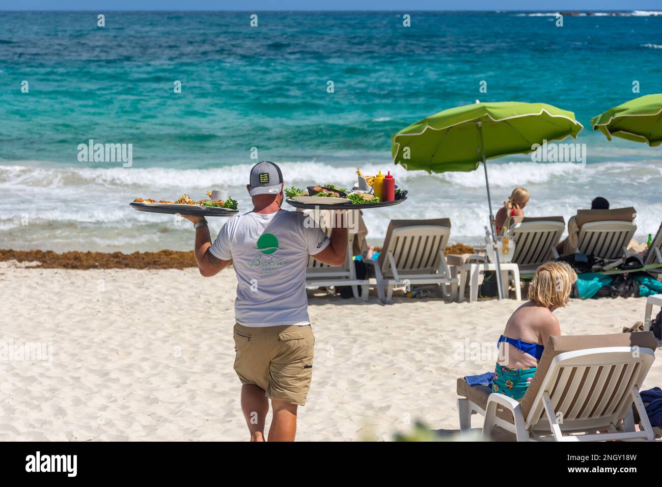 Cameriere che cerca cibo su Bikini Beach, Orient Bay (Baie Orientale), St Martin (Saint-Martin), piccole Antille, Caraibi Foto Stock