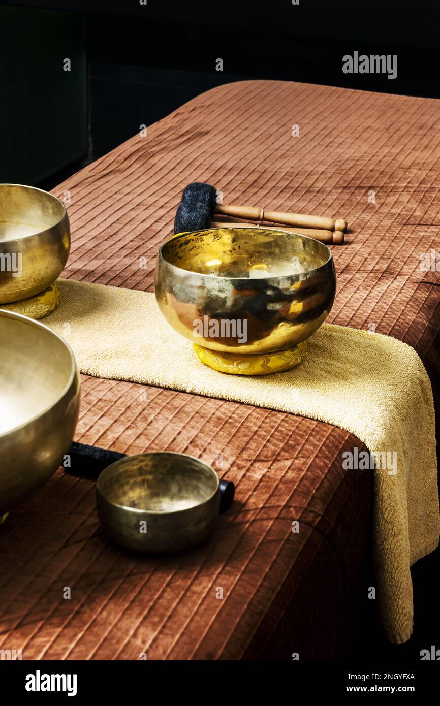 Ciotole tibetane in metallo per il rituale dei massaggi rilassanti su un tavolo con asciugamani Foto Stock