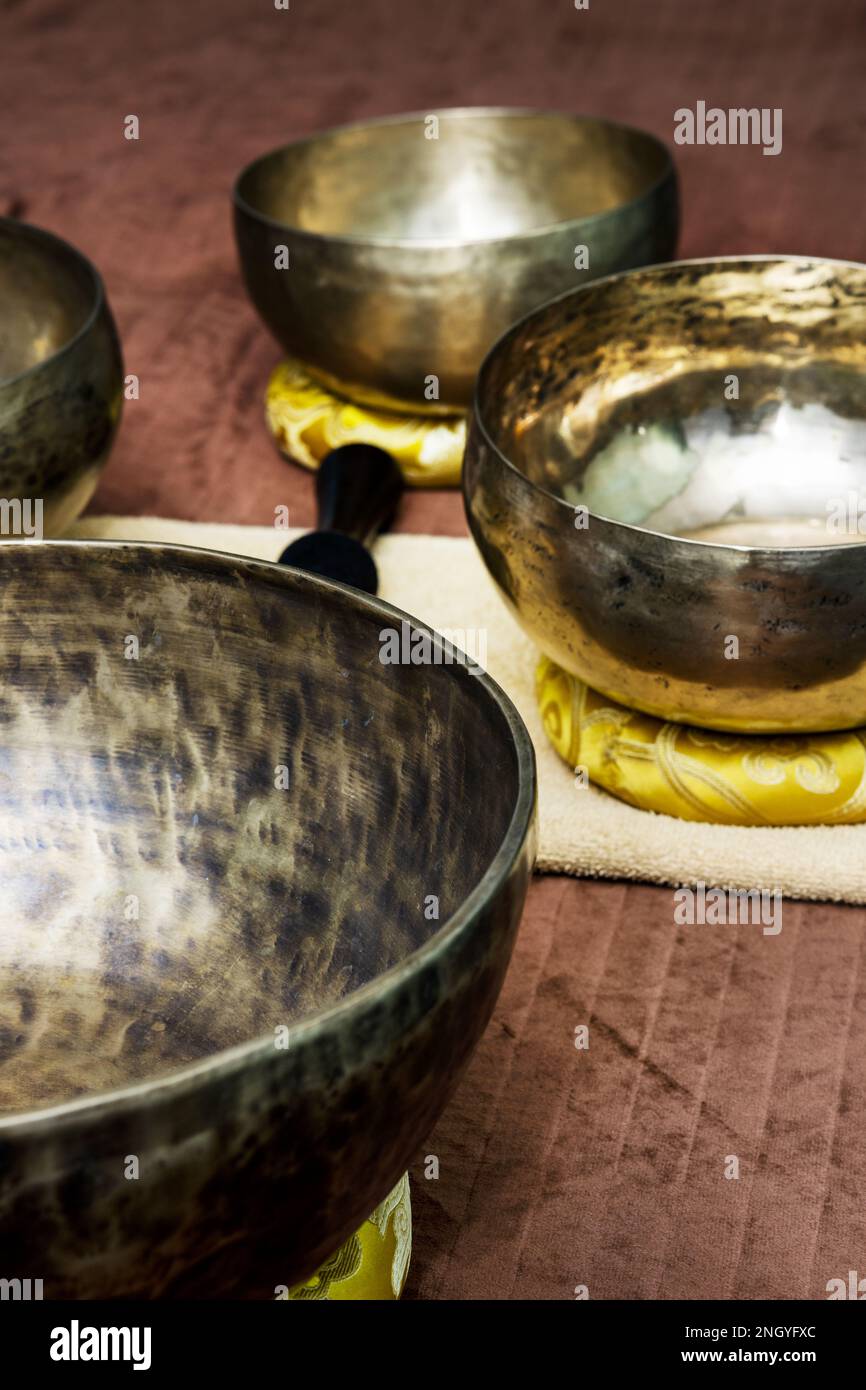 Grandi contenitori in metallo tibetano per il rituale del massaggio rilassante su un tavolo con asciugamani, panni e oggetti simili Foto Stock