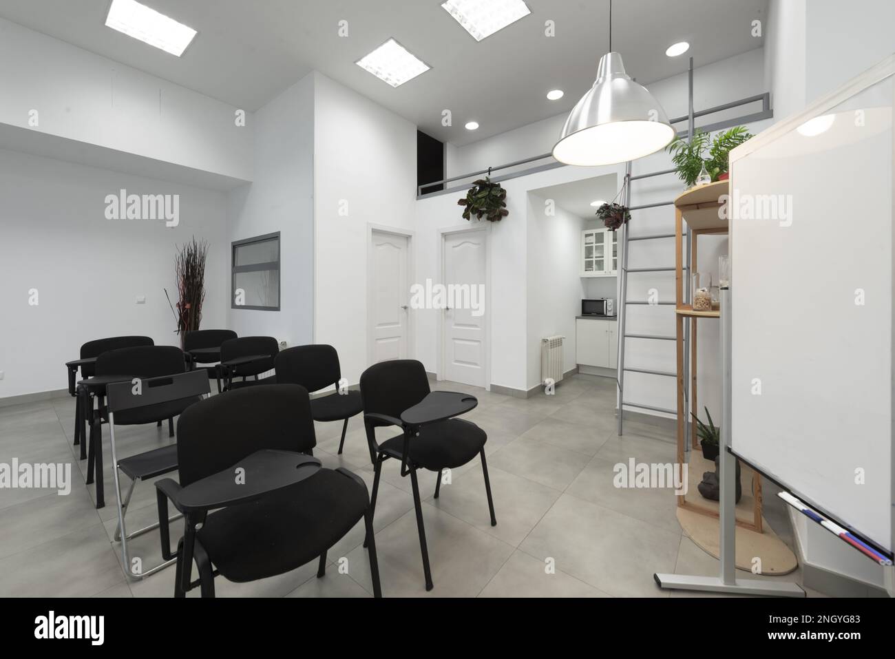 Aula vuota con sedili neri con tavolo pieghevole e lavagna bianca con pennarelli cancellabili Foto Stock