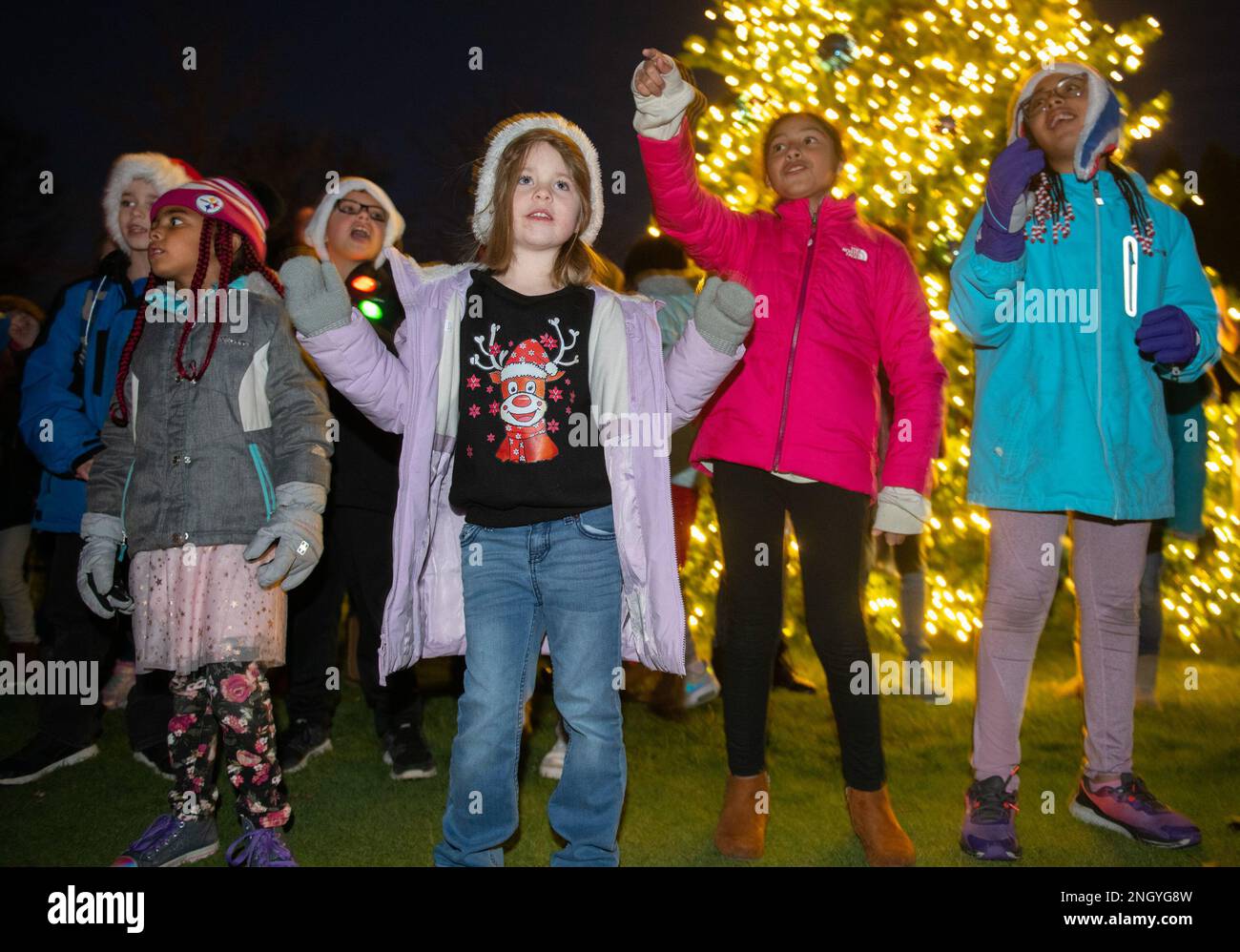 I bambini del programma School-Age presso la base dell'aeronautica militare Wright-Patterson, Ohio, cantano le carole natalizie durante la cerimonia annuale dell'illuminazione degli alberi, il 1 dicembre 2022, presso il campo da golf Prairie Trace. Dopo l'illuminazione, le famiglie hanno avuto la possibilità di accarezzare delle renne, prendere un rinfresco e scattare foto con Babbo Natale. Foto Stock