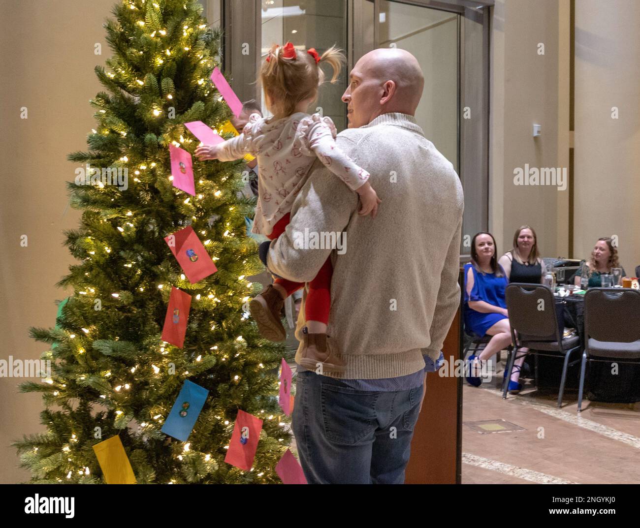221201-N-MR862-246 OKLAHOMA CITY, OTTOBRE (01 dicembre 2022) Maestro-at-Arms Capo Petty Officer Asher Wann, attaccato alla Strategic Communications Wing (SCW) 1, e sua figlia partecipare allo scambio di regali al SCW-1 Annual Christmas Party. I nomi dei marinai sono disegnati e chiesti di scegliere una busta dall'albero, come il bambino di questo marinaio è visto fare il 01 2022 dicembre. SCW-1 è un comando tenant presso la base dell'aeronautica militare Tinker, che garantisce la sicurezza nazionale attraverso la dissuasione delle ambizioni nucleari contraddittorie. Foto Stock