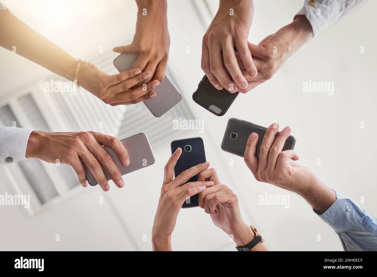 I team intelligenti utilizzano la tecnologia intelligente. Un gruppo di foto a basso angolo di un gruppo di colleghi che utilizzano i loro smartphone in sincronia utilizzando il loro smartphone Foto Stock