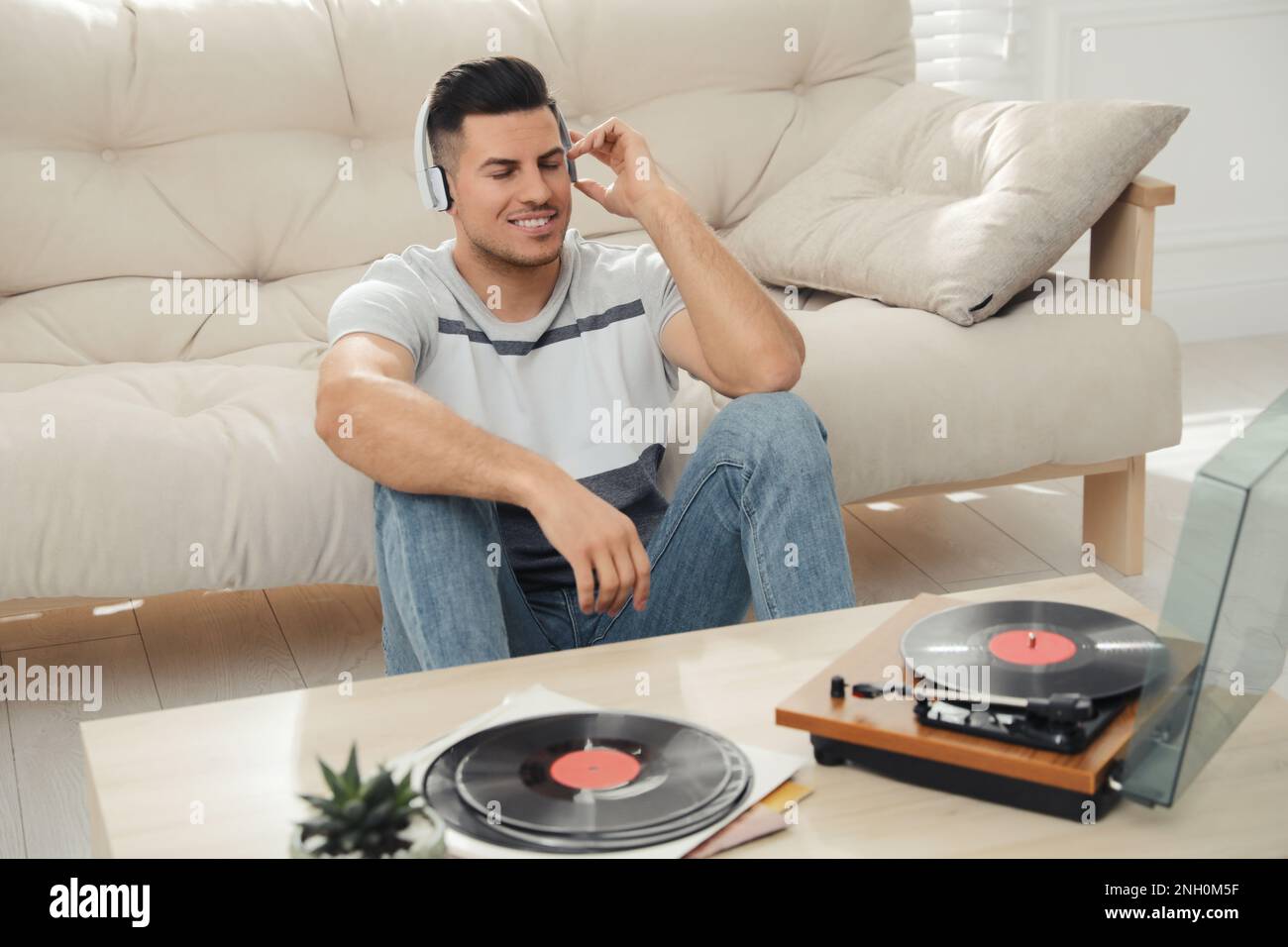 Un uomo felice che ascolta la musica con il giradischi a casa Foto Stock