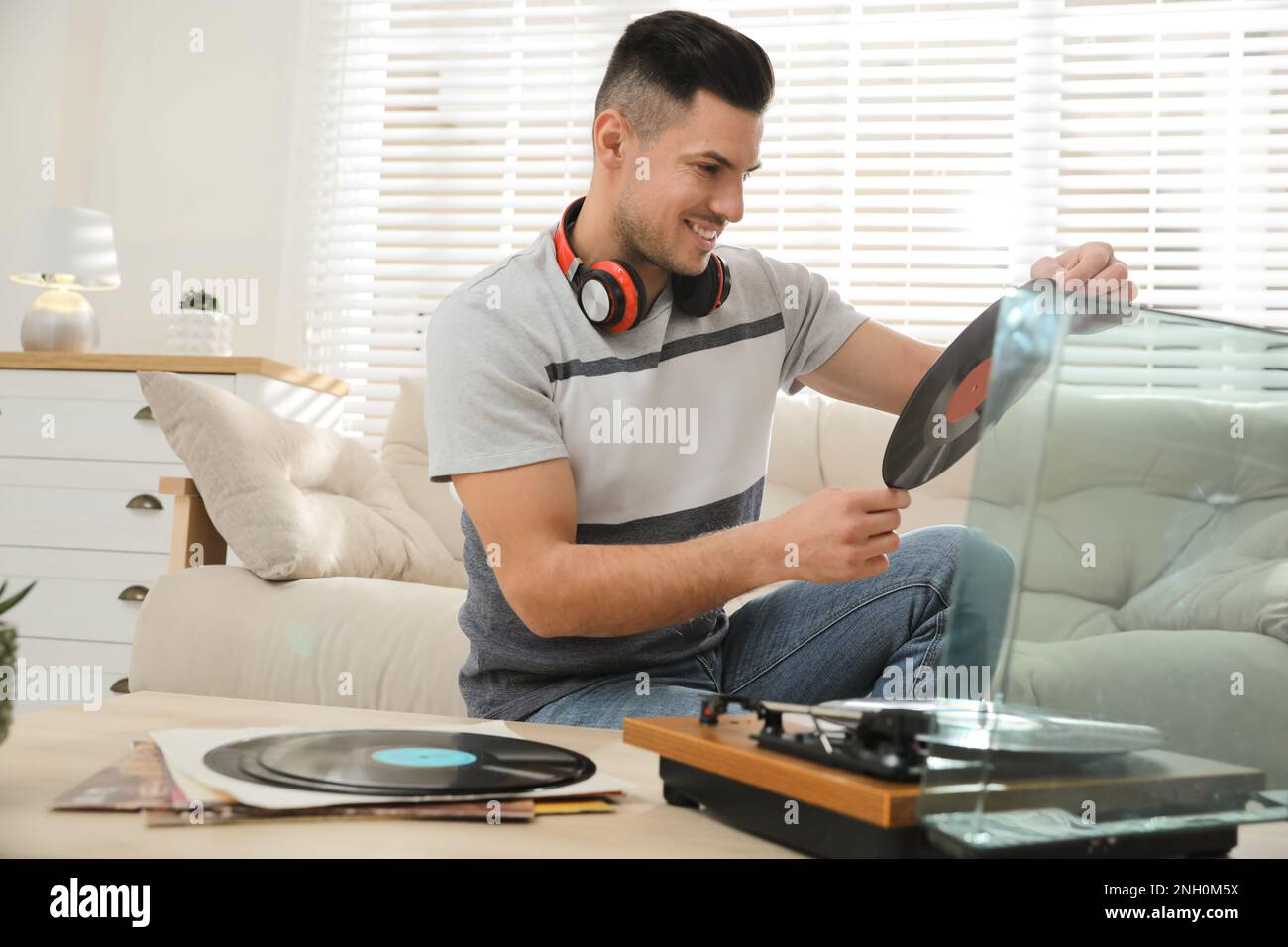 Un uomo felice che sceglie il disco in vinile per giocare con il giradischi a casa Foto Stock