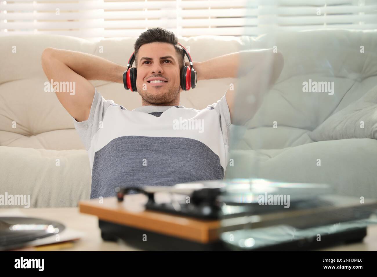 Un uomo felice che ascolta la musica con il giradischi a casa Foto Stock