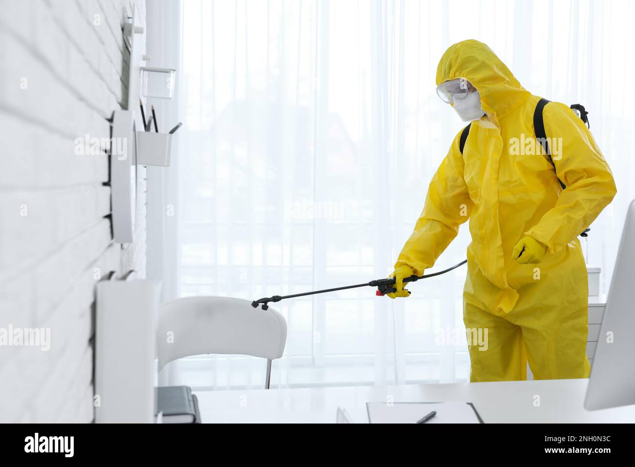 Dipendente in tuta protettiva igienizzante ufficio. Disinfezione medica Foto Stock